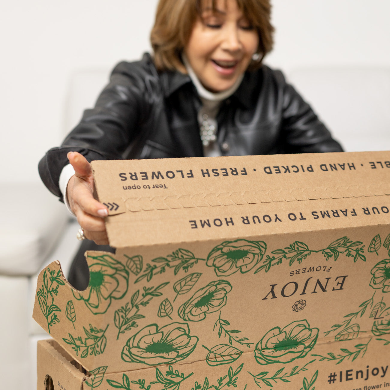 A mother opens a box of farm-fresh flowers from the Enjoy Flowers Garden Collection featuring 30-35 stems.