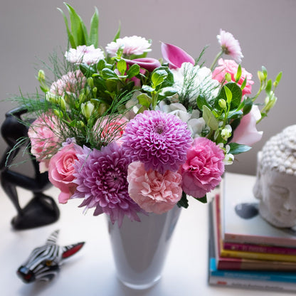 A Garden Collection bouquet of 30-35 stems of Callas, roses, chrysanthemum, and other farm-fresh varieties sits in a white vase.