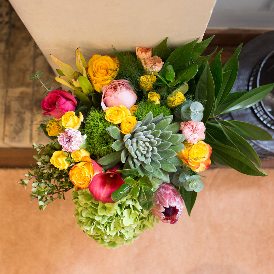 A Designer Collection bouquet features Callas, protea, roses, succulents, hydrangea, green trick, and other premium varieties.