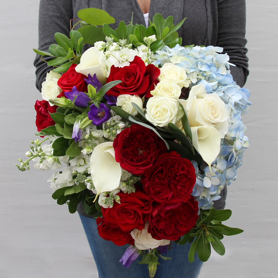 A Designer Collection bouquet features red and white roses, hydrangea, Callas, and other premium varieties. 